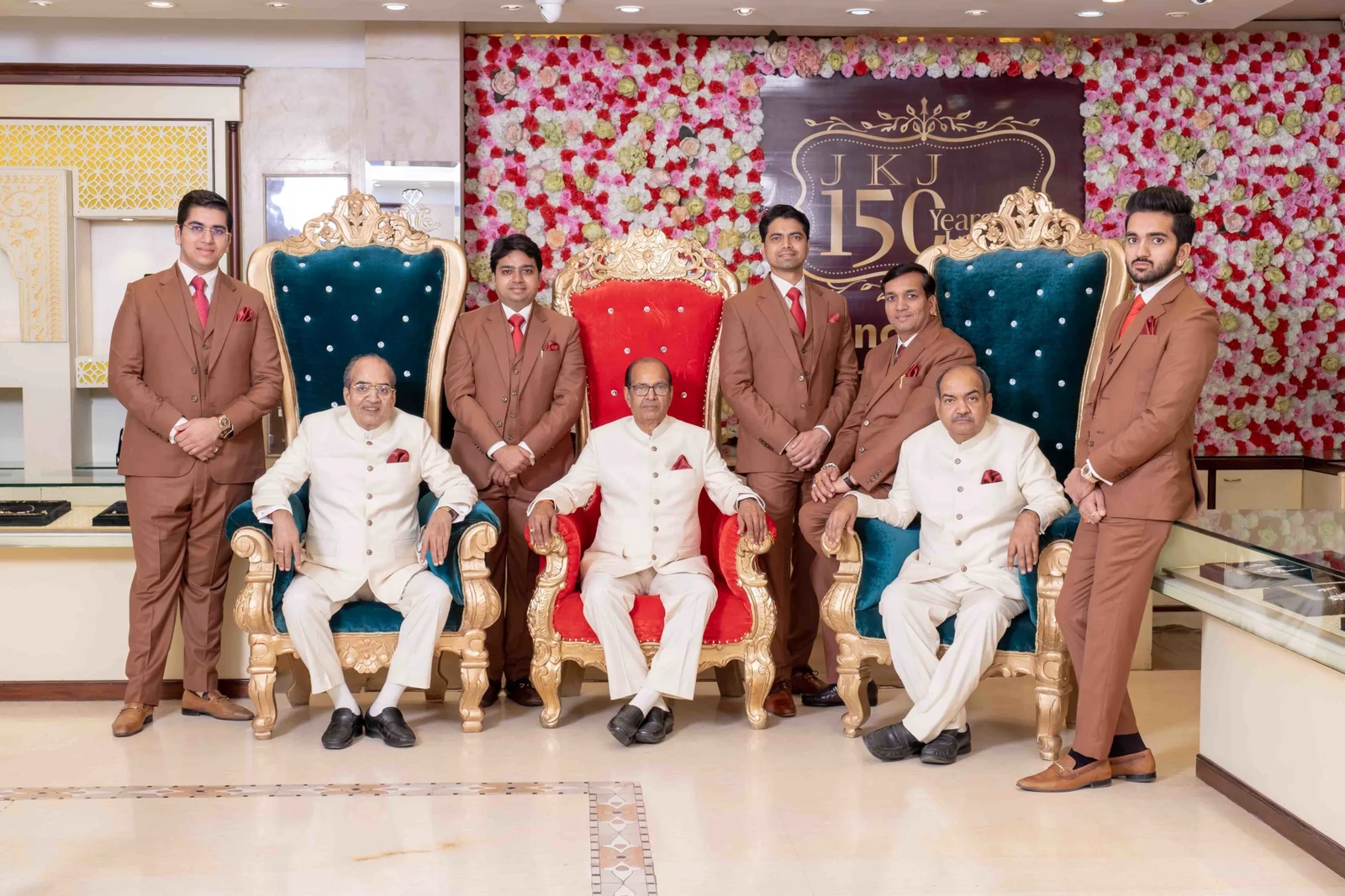 Eight members of the Mosun family at a JKJ showroom, in front of a JKJ 150 Years display